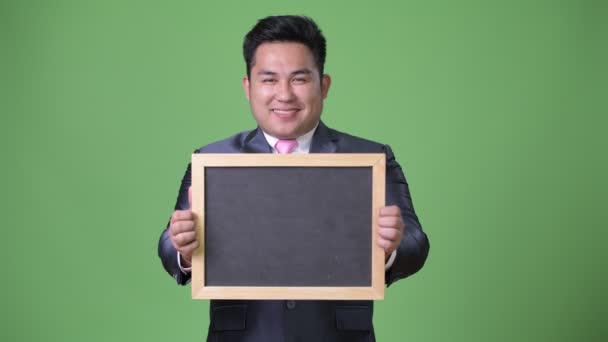 Young handsome overweight Asian businessman against green background — Stock Video