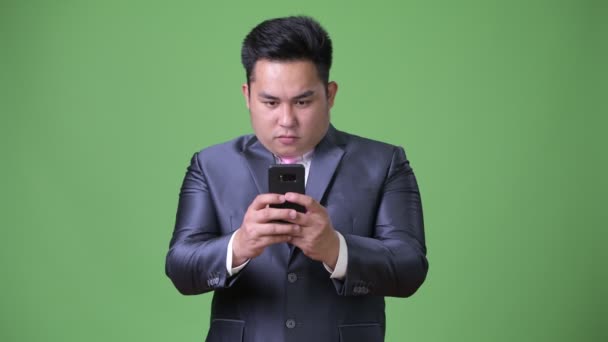 Young handsome overweight Asian businessman against green background — Stock Video