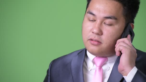 Junge hübsche übergewichtige asiatische Geschäftsmann vor grünem Hintergrund — Stockvideo