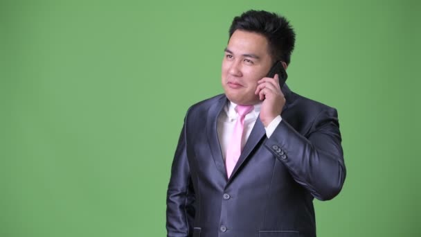 Genç yakışıklı kilolu Asya işadamı yeşil bir arka plana dayanır — Stok video