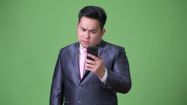 Ung snygg överviktiga asiatiska affärsman mot grön bakgrund — Stockvideo