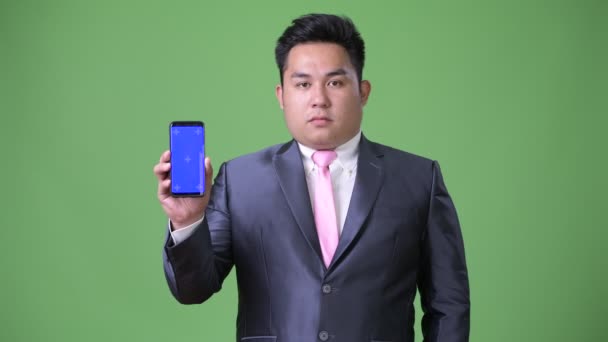 Молодий красивий надмірна вага азіатських бізнесмен на зеленому тлі — стокове відео