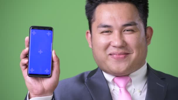 太りすぎの若いハンサムな緑の背景にアジア系のビジネスマン — ストック動画