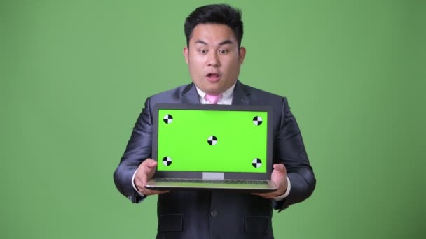 Young handsome overweight Asian businessman against green background — Stock Video