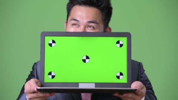Young handsome overweight Asian businessman against green background — Stock Video