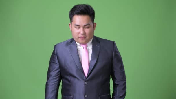 Молодий красивий надмірна вага азіатських бізнесмен на зеленому тлі — стокове відео
