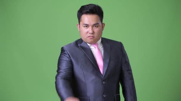 Young handsome overweight Asian businessman against green background — Stock Video