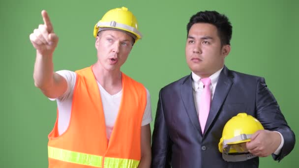 Скандинавский рабочий-строитель и азиатский бизнесмен работают вместе — стоковое видео