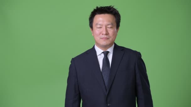 Rijpe Japanse zakenman tegen groene achtergrond — Stockvideo
