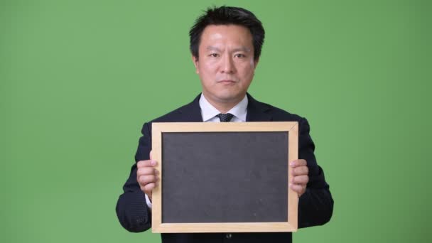 Зрелый японский бизнесмен на зеленом фоне — стоковое видео
