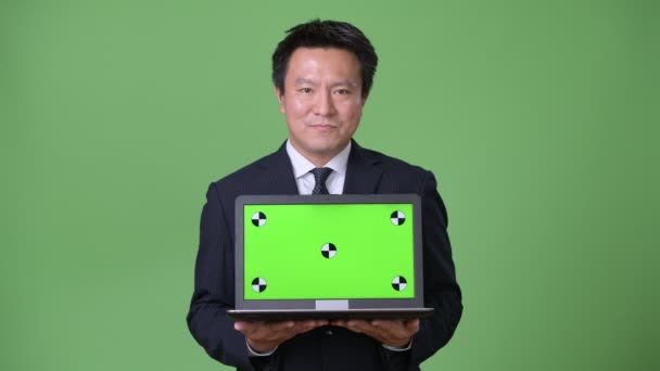 Mature Japanese businessman against green background — Stock Video