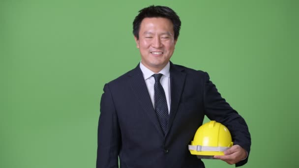 Mature Japanese businessman against green background — Stock Video