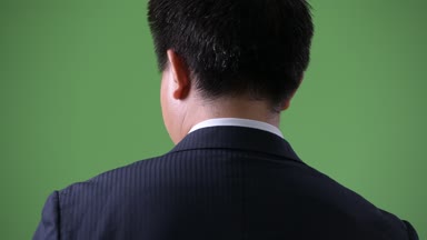 Olgun Japon işadamı yeşil bir arka plana dayanır