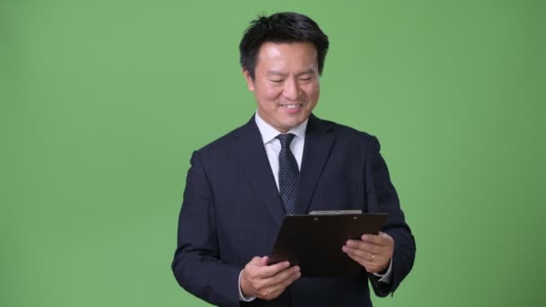 Mature Japanese businessman against green background — Stock Video