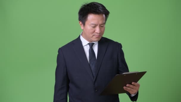 Olgun Japon işadamı yeşil bir arka plana dayanır — Stok video