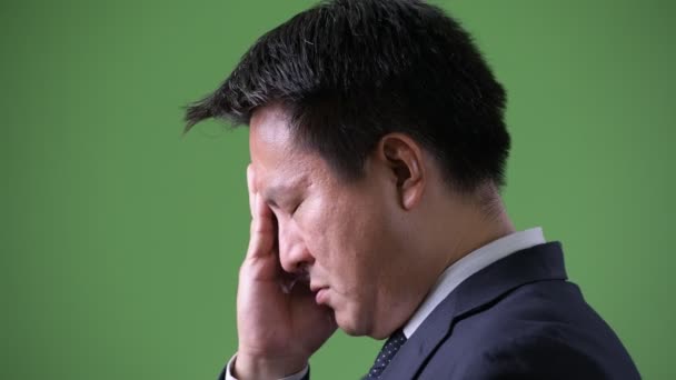 Rijpe Japanse zakenman tegen groene achtergrond — Stockvideo