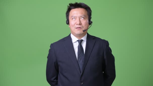 Mature Japanese businessman against green background — Stock Video