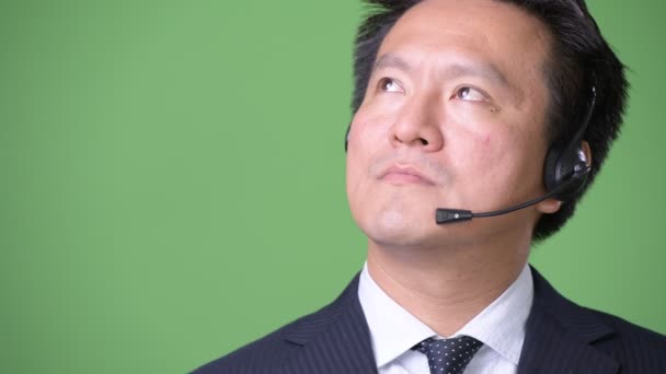 Mature Japanese businessman against green background — Stock Video