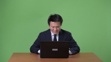 Olgun Japon işadamı yeşil bir arka plana dayanır