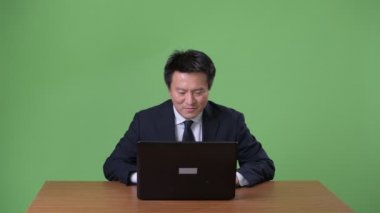 Olgun Japon işadamı yeşil bir arka plana dayanır