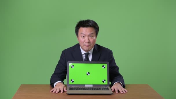 Зрілі японський бізнесмен на зеленому тлі — стокове відео