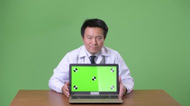 Olgun Japon adam doktor yeşil bir arka plana dayanır