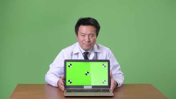 Зрелый японский врач на зеленом фоне — стоковое видео