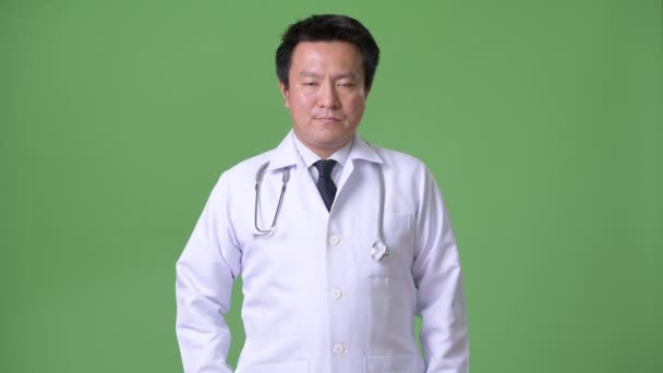 Mature Japanese man doctor against green background — Stock Video