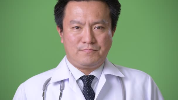 Mature Japanese man doctor against green background — Stock Video