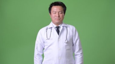 Olgun Japon adam doktor yeşil bir arka plana dayanır
