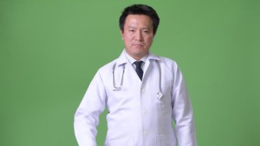 Olgun Japon adam doktor yeşil bir arka plana dayanır