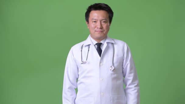 Mature Japanese man doctor against green background — Stock Video