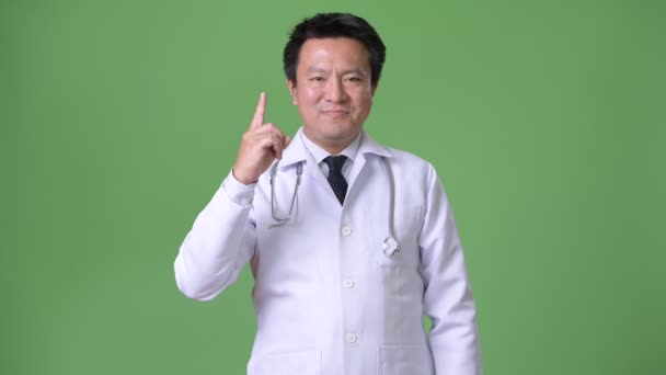 Mature Japanese man doctor against green background — Stock Video