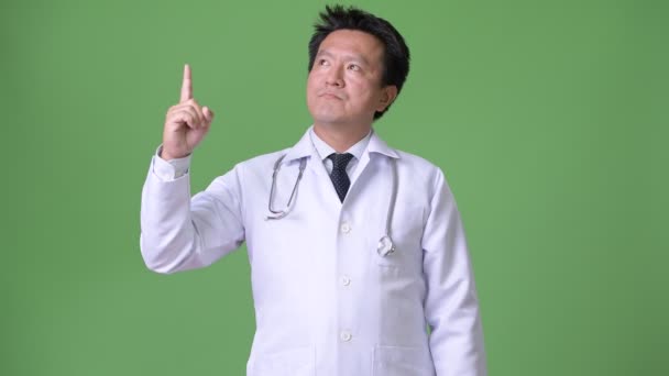 Зрелый японский врач на зеленом фоне — стоковое видео