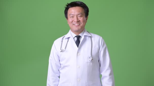 Mature Japanese man doctor against green background — Stock Video