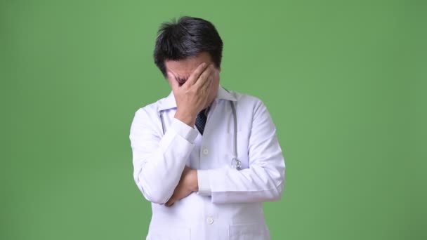 Mature Japanese man doctor against green background — Stock Video