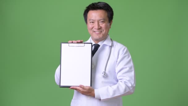 Mature Japanese man doctor against green background — Stock Video