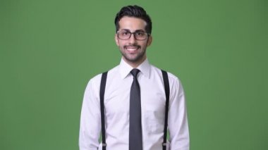 Genç yakışıklı sakallı İranlı işadamı yeşil bir arka plana dayanır