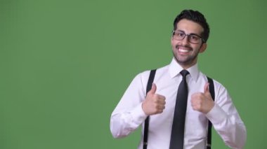 Genç yakışıklı sakallı İranlı işadamı yeşil bir arka plana dayanır