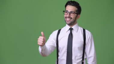 Genç yakışıklı sakallı İranlı işadamı yeşil bir arka plana dayanır