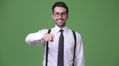 Genç yakışıklı sakallı İranlı işadamı yeşil bir arka plana dayanır