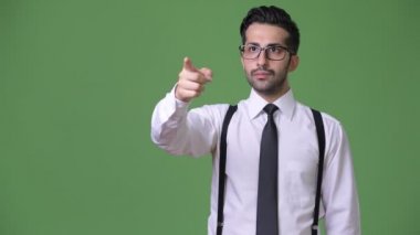 Genç yakışıklı sakallı İranlı işadamı yeşil bir arka plana dayanır