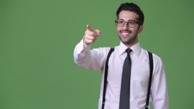 Genç yakışıklı sakallı İranlı işadamı yeşil bir arka plana dayanır
