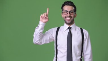 Genç yakışıklı sakallı İranlı işadamı yeşil bir arka plana dayanır