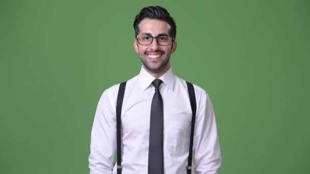 Young handsome bearded Persian businessman against green background — Stock Video