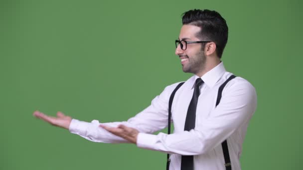 Young handsome bearded Persian businessman against green background — Stock Video