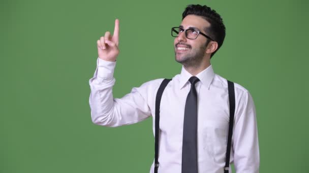 Young handsome bearded Persian businessman against green background — Stock Video