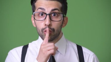 Genç yakışıklı sakallı İranlı işadamı yeşil bir arka plana dayanır