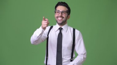 Genç yakışıklı sakallı İranlı işadamı yeşil bir arka plana dayanır