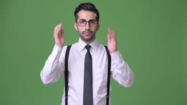 Genç yakışıklı sakallı İranlı işadamı yeşil bir arka plana dayanır — Stok video